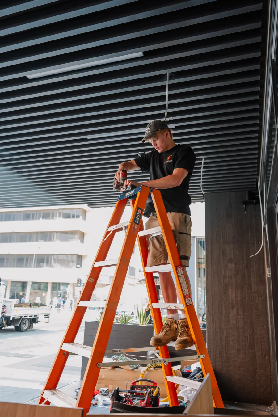 Up the ladder working on a ceiling under a slatted soffit